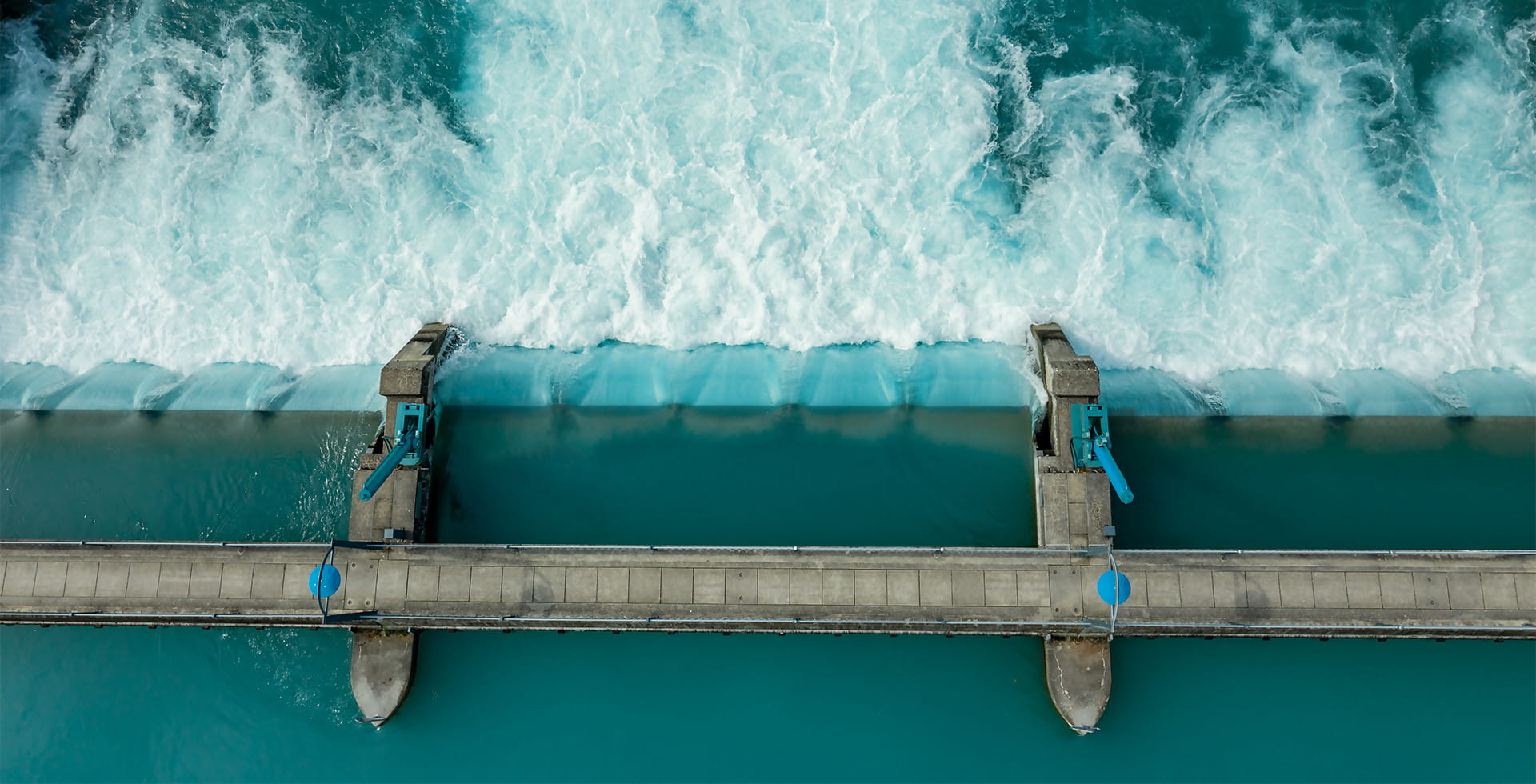 Aerial image of water flowing fast through a dam