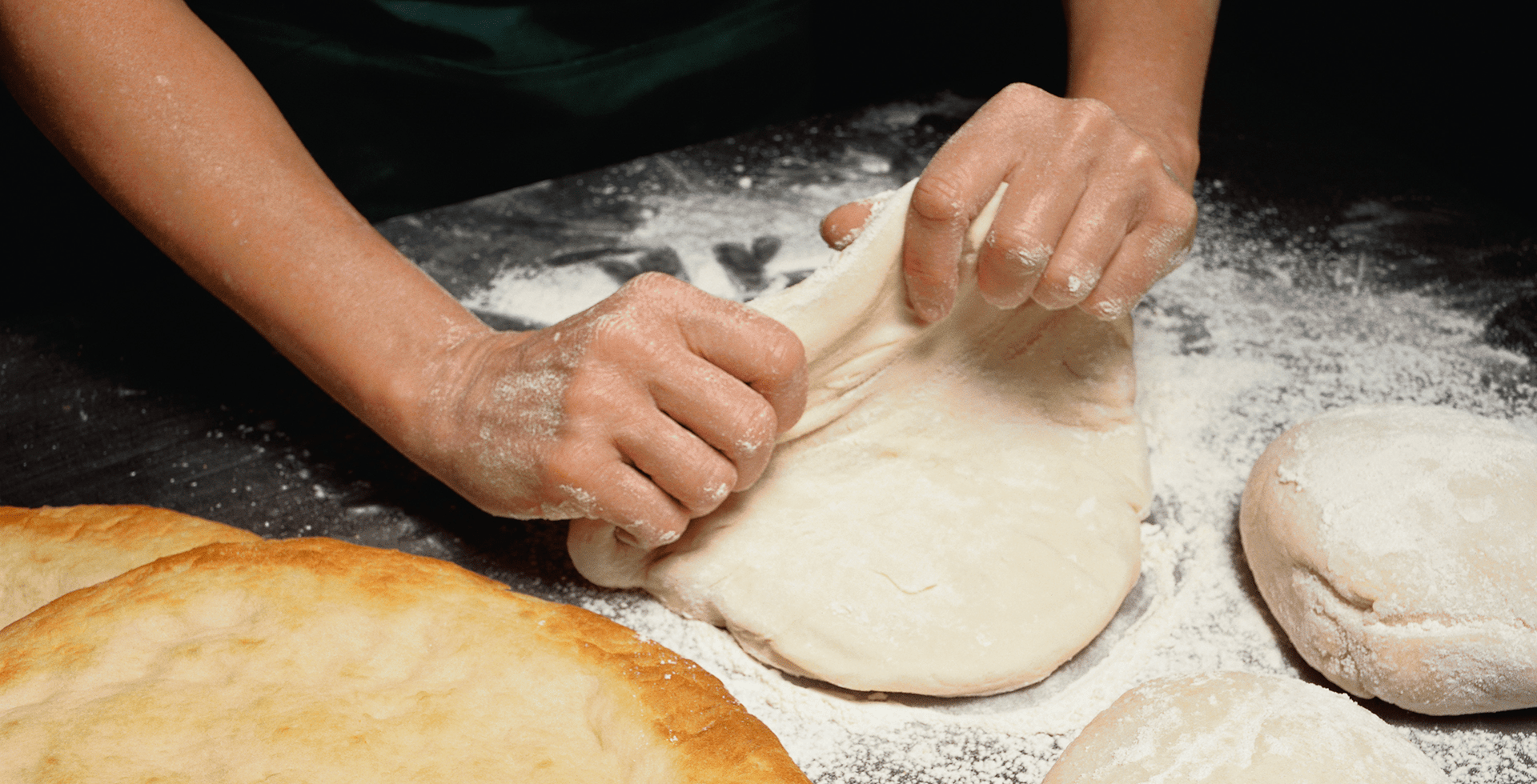 Close up image of a person's hands kneading dough to make loaves of bread